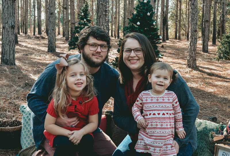 Me and my family sitting in the woods with Christmas trees in the background